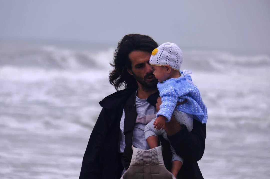 Viktor holding his daughter near the sea