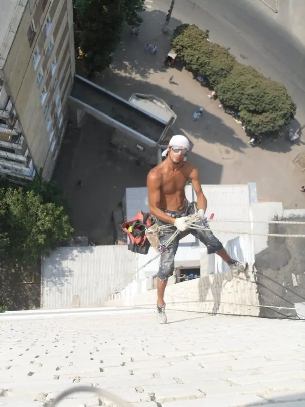 Viktor hanging on ropes with tools on a high-rise